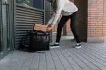 Man in White Dress Shirt and Blue Denim Jeans Holding Black Luggage Bag