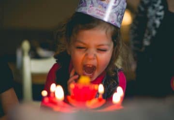 shallow focus photography of toddler blowing cake candles