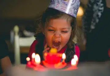 shallow focus photography of toddler blowing cake candles