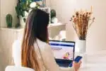 a woman sitting at a table using a laptop computer