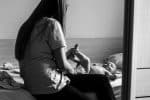 woman in white shirt and black pants sitting on bed